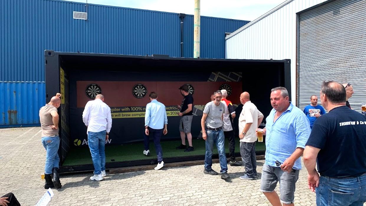 Modified black 20 foot dart container for tournament with four dart boards and fake green grass at ContainerID in Antwerp for sale or hire