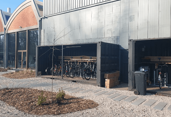 Two black Outdoor storage solution for bikes with custom 20 foot shipping container turned to bike shed with open side access and bike rack in Antwerp by ContainerID